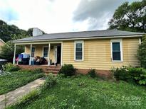 Quaint yellow home featuring a covered porch with storage and a small front yard at 3396 Farm Lake Sw Dr, Concord, NC 28027