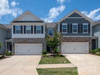 Charming townhome featuring stone accents, a two-car garage, and a well-manicured lawn with beautiful landscaping at 4177 Steel Way, Sherrills Ford, NC 28673