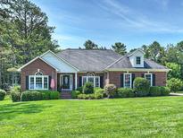 Charming brick home with manicured lawn, mature trees, and an American flag at 5921 Meadowmere Dr, Monroe, NC 28110