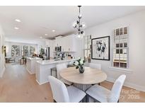 Bright dining area with modern light fixture, light wood table and chairs, and white cabinets at 1223 E 16Th St # 13, Charlotte, NC 28205