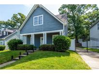 Charming blue two-story home with a well-maintained front yard and a gated driveway at 1226 Rising Oak Dr, Charlotte, NC 28206