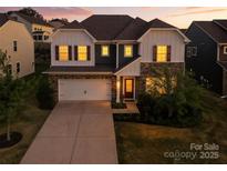 Charming two-story home featuring a stone facade, attached garage, and manicured lawn at dusk at 15119 Oleander Dr, Charlotte, NC 28278
