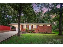 Charming brick home with a carport, well-maintained lawn, and mature trees offering ample shade and curb appeal at 1535 Maplewood Ave, Lancaster, SC 29720