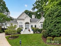 Beautiful white home featuring a well-manicured lawn and lush, mature landscaping surrounding the property at 19205 Hidden Cove Ln, Cornelius, NC 28031