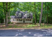 Charming two-story home with a inviting front porch and dormer windows nestled among mature trees at 203 Hickory Wood Dr, Kannapolis, NC 28083