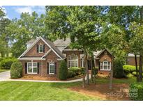 Charming brick home with mature trees, lush landscaping, and manicured lawn at 2241 Flagstick Dr, Matthews, NC 28104