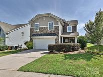 Charming two-story home features a manicured lawn, stone accents, and a two-car garage at 3009 Canopy Dr, Indian Trail, NC 28079