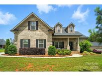 Charming brick home featuring a well-manicured lawn, dark shutters, and a welcoming front porch at 3256 Fairmead Dr, Concord, NC 28025