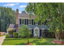 Charming two-story home with blue siding, black shutters, brick chimney, and well-manicured lawn at 4911 Rivergreen Ln, Charlotte, NC 28227