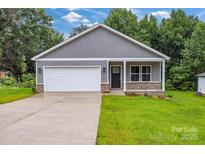 Charming single-story home featuring a covered porch, gray siding, and a two-car garage at 5185 Grand Canyon Rd, Concord, NC 28027