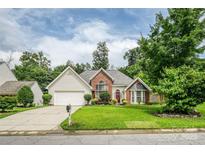 Charming brick and vinyl home featuring a lush, well-manicured lawn and mature trees at 6414 Goldenblush Cir, Charlotte, NC 28269
