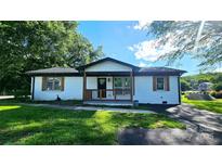 Charming single-story home with white brick, wooden porch, shutters, and well-maintained front lawn at 703 Central Nw Dr, Concord, NC 28027