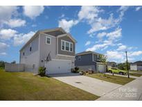 Two-story home featuring light siding, attached two-car garage, and well-maintained front lawn under a partly cloudy sky at 1010 Harry Ct, Albemarle, NC 28001