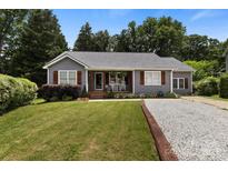 Charming home features a manicured lawn and inviting front porch with classic rocking chairs and wooden shutters at 1507 Breckenwood Dr, Rock Hill, SC 29732