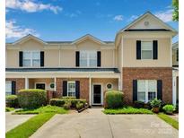 Charming townhome with a brick and tan siding, complemented by manicured landscaping and dark shutters at 222 Ross Moore Ave, Charlotte, NC 28205
