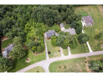 An aerial view of a property nestled among trees, featuring a long driveway and expansive lawn at 3874 Willow Grove Ln, Concord, NC 28025