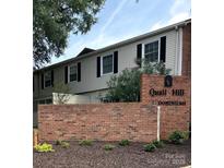 Exterior view of condo with brick base, gray siding, and black shutters in a meticulously maintained community at 5941 Quail Hollow Rd # F, Charlotte, NC 28210