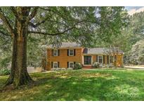 Charming two-story brick home with a well-manicured lawn, mature trees, and classic black shutters at 6117 Yellowood Rd, Charlotte, NC 28210