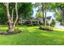 Inviting home featuring a lush green lawn, mature trees, and manicured landscaping at 802 E Franklin St, Monroe, NC 28112