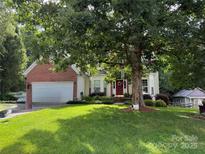 Charming two-story home with attached garage, red door, manicured lawn, and mature landscaping at 130 Nims Spring Dr, Fort Mill, SC 29715