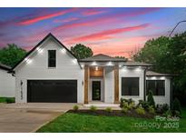 Charming white brick home featuring a black garage door, wooden pillars, and professional landscaping at 1622 Burtonwood Cir, Charlotte, NC 28212
