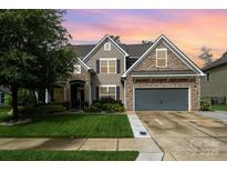 Beautiful home with warm tones, manicured lawn, and stone accents during a colorful sunset at 183 Canoe Pole Ln, Mooresville, NC 28117