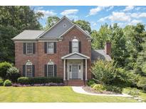 Charming brick home with a manicured lawn, mature trees, and gray shutters at 205 Rosedale Ln, Matthews, NC 28105