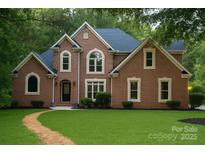 Charming brick home featuring lush lawn, manicured shrubbery, and complementary blue roofing at 3011 Mckee Rd, Charlotte, NC 28270