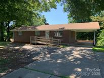 Charming one-story brick home with a ramp, carport and mature trees creating a welcoming curb appeal at 3484 S Hwy 127 Hwy, Hickory, NC 28602