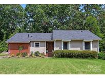 Charming ranch-style home features lush front lawn, mature trees and updated landscaping with detailed masonry facade at 5922 Sullins Rd, Charlotte, NC 28214