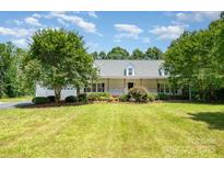 Charming single-story home with a covered porch and lush landscaping, framed by mature trees at 6811 Kluttz Rd, Concord, NC 28025
