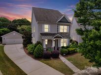 Charming two-story home with landscaped yard, stone accents, and detached garage at sunset at 8702 Aspinwall Dr, Charlotte, NC 28216