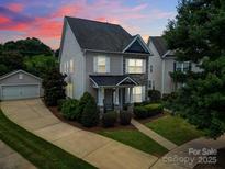 Charming two-story home featuring gray siding, stone accents, a manicured lawn, and a detached garage at 8702 Aspinwall Dr, Charlotte, NC 28216