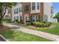 Charming townhome with brick facade, green shutters, and beautifully landscaped front yard at 9728 Blossom Hill Dr, Huntersville, NC 28078