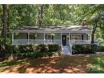 Charming single-story home featuring a welcoming front porch with meticulous landscaping and mature trees at 1118 Brookwood Dr, Stanley, NC 28164