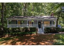 Charming home with a welcoming front porch, lush landscaping, and inviting curb appeal amidst a leafy surrounding at 1118 Brookwood Dr, Stanley, NC 28164