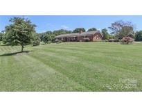 Expansive front lawn leads to a brick ranch-style home with a neatly manicured landscape at 116 Deer Trail Rd, Statesville, NC 28677