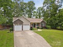 Charming ranch-style home boasts a manicured lawn, mature trees, and a two-car garage, perfect for suburban living at 1313 Western Hills Ln, Vale, NC 28168
