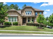 Charming two-story home with a stone facade, manicured lawn, and beautifully landscaped front yard at 16402 Doves Canyon Ln, Charlotte, NC 28278