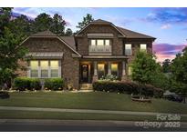Charming stone home featuring a well-manicured lawn and professional landscaping at 16402 Doves Canyon Ln, Charlotte, NC 28278