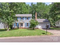 Charming two-story home with light gray siding, blue shutters, manicured lawn and mature trees at 2012 Killarney Pl, Charlotte, NC 28262