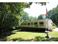 Inviting exterior of a white raised home with a wrap-around porch and a lush green lawn at 220 Singing Pine Dr, Clover, SC 29710