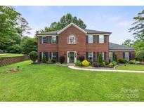 Charming brick home with manicured lawn, dark shutters, and inviting front entrance at 5302 Fairgrove Ln, Harrisburg, NC 28075