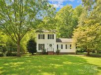 Charming two-story home with white siding, black shutters, and a well-manicured lawn surrounded by mature trees at 5828 Wilora Lake Rd, Charlotte, NC 28212