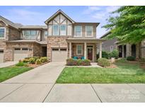 Charming townhome featuring a stone facade, attached garage, and inviting front porch at 7322 Dulnian Way, Charlotte, NC 28278