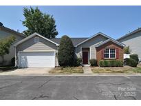 Charming single-story home with a well-manicured lawn and a cozy red front door, complemented by a two-car garage at 8655 Meadowmont View Dr, Charlotte, NC 28269
