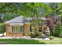 Charming brick home with a well-manicured lawn and lush landscaping, nestled beneath the shade of mature trees at 10007 Hillspring Dr, Huntersville, NC 28078