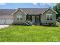Charming one-story home with lush green lawn, stone accents, and inviting front porch seating at 104 Nottingham Dr, Maiden, NC 28650