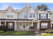 Charming townhome with rocking chairs on the porch, landscaped yard, and inviting curb appeal at 11023 Kinston Ridge Pl, Charlotte, NC 28273