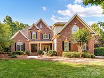 Charming brick home featuring lush landscaping, a manicured lawn, and a welcoming front porch at 15009 Fanning Manor Ct, Charlotte, NC 28277